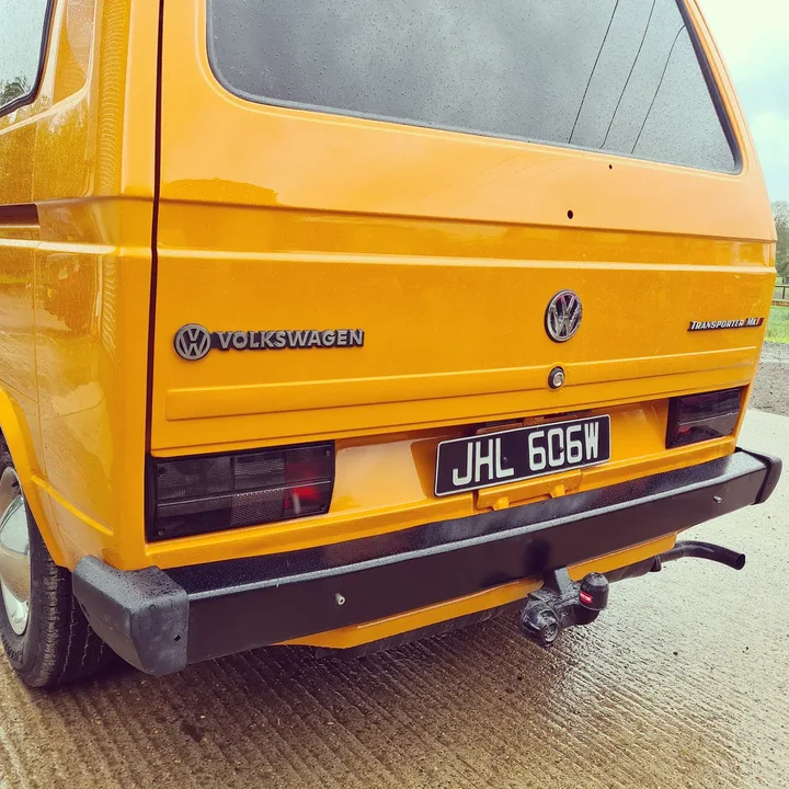 Close view of a Volkswagen T25 camper tailgate, rear lights, bumper and tow bar.