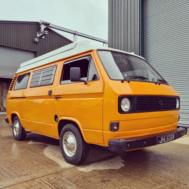Volkswagen T25 camper photographed from the front quarter beside the workshop roller door.