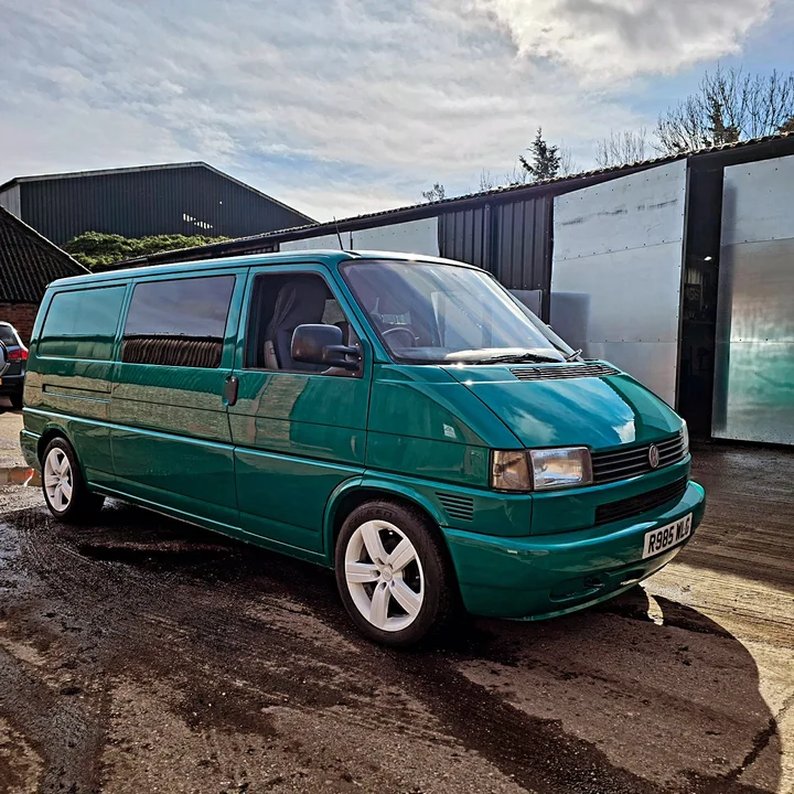 Volkswagen T4 Transporter with alloy wheels and side windows parked beside the workshop building.