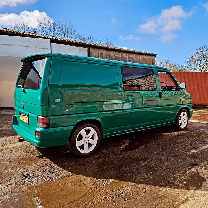 Rear three-quarter view of a Volkswagen T4 Transporter with alloy wheels outside the workshop.