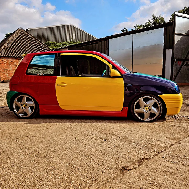 Multicolour car photographed outside the workshop.
