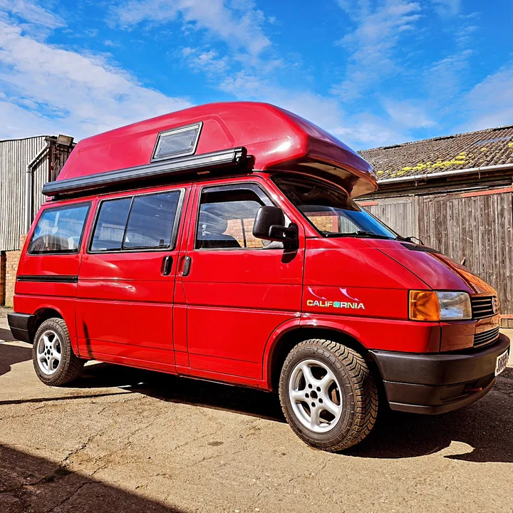 Volkswagen T4 California camper with a high roof photographed from the front quarter outside the workshop.
