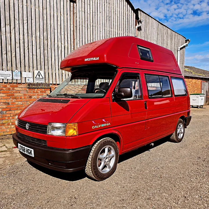 Front three-quarter view of a Volkswagen T4 California camper with a high roof and black bumpers.