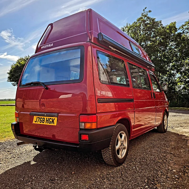 Rear three-quarter view of a Volkswagen T4 California camper with a high roof and tinted side windows.