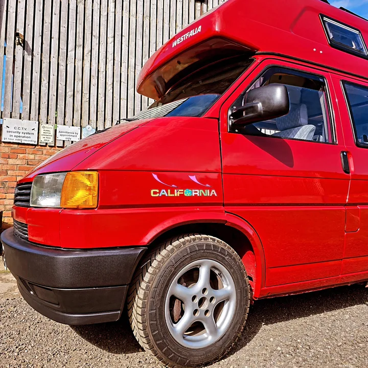 Close view of a Volkswagen T4 California camper front wing, wheel, headlight and bumper.
