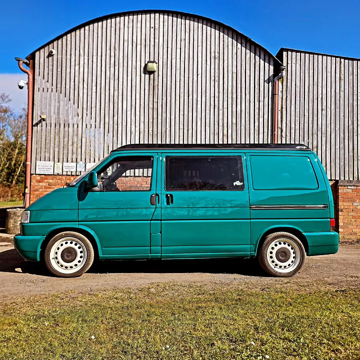 Full side profile of a Volkswagen T4 Transporter with dark side windows and a roof fitting.