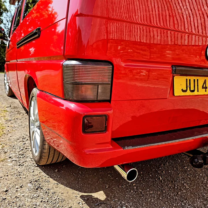 Close view of the red T4 Transporter rear corner, tail light, bumper and exhaust outlet.