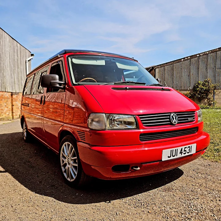 Red T4 Transporter photographed from the front with its Volkswagen grille, headlights and red bumper visible.