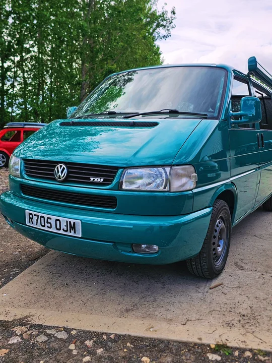 Teal Volkswagen T4 Transporter front showing the Volkswagen grille badge, headlights and body-coloured bumper.