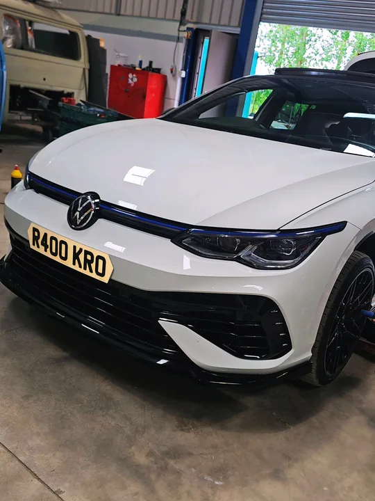 White Volkswagen Mk8 Golf photographed indoors with black wheels and dark front bumper trim.