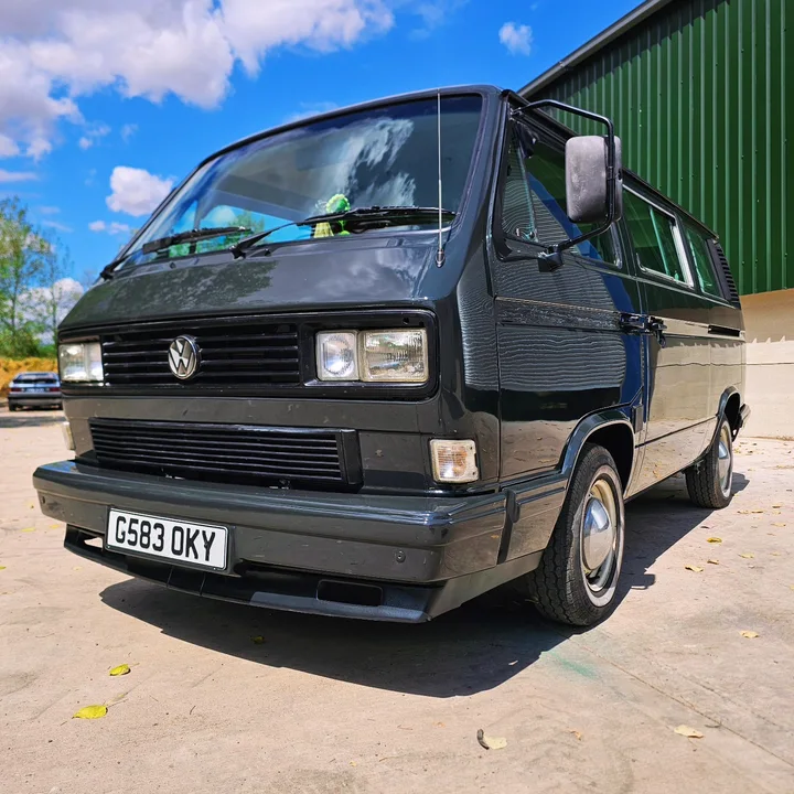 Front three-quarter view of a black T25 camper showing its Volkswagen grille badge and rectangular headlights.