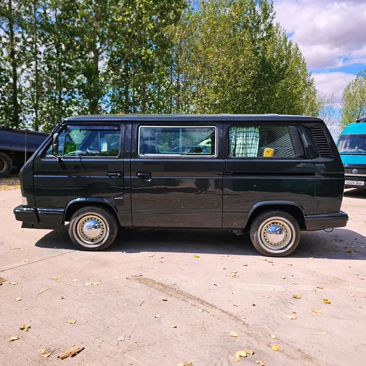 Full side profile of a black Volkswagen T25 camper with silver wheel covers.