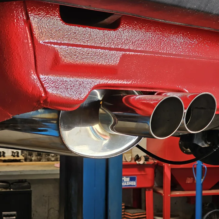 Close view of a red textured underside finish around polished twin exhaust outlets